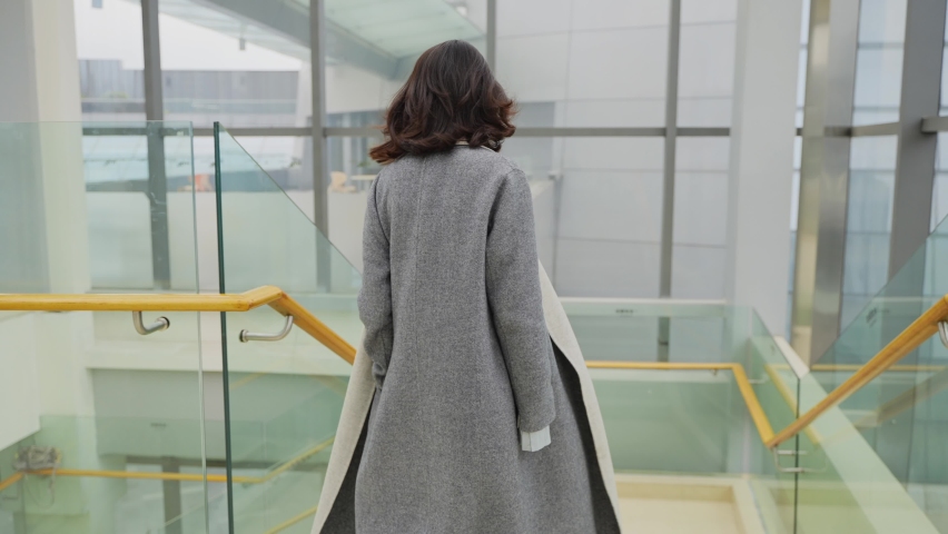4K slow motion Asian businesswoman in coat walking down the stairs in the office building