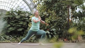 Senior woman practicing yoga while sitting on yoga mat. Side view footage of senior woman practicing yoga in park. Close up footage of senior woman in park practicing yoga. Healthy lifestyle concept - Powered by Shutterstock - Get 15% off with code: PIKWIZARD15