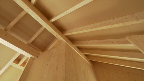Beautiful view of the massive ceiling beams of a modern cross laminated timber house. Gorgeous hardwood structure of the ceiling of a contemporary glue laminated housing project under construction.