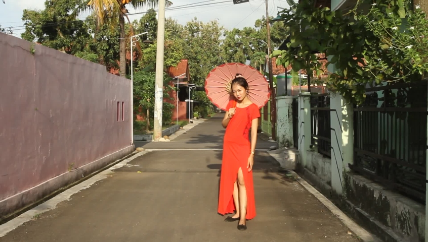 Asian girl in red dress posing in the yard of the house