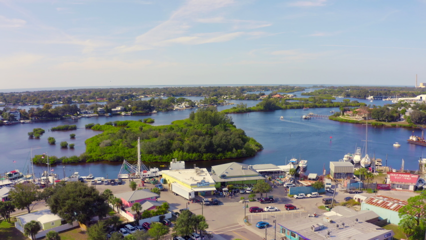 Flying Over Boats Docked by Restaurants and Small Island on Bay in Florida