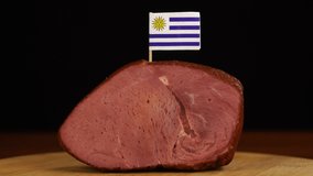 Person placing decorative Uruguayan flag toothpicks into piece of red meat. - Powered by Shutterstock - Get 15% off with code: PIKWIZARD15
