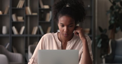 Focused young african ethnic female freelancer businesswoman working on computer at home office, thinking on difficult task or considering problem solution. Smart 25s biracial girl studying distantly.