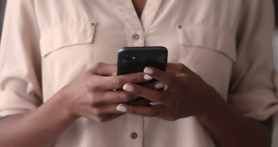 Close up young mixed race african woman holding smartphone in hands, swiping pages in dating application, web surfing information, choosing goods in internet store, shopping online using cellphone. Royalty-Free Stock Footage #1070466073
