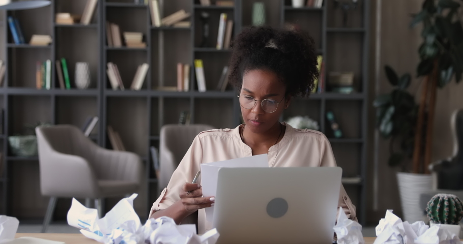 Unhappy young african ethnicity businesswoman in eyeglasses, doing financial paperwork, feeling stressed at home office. Anxious 25s biracial female employee crumpling documents, leaving workplace. Royalty-Free Stock Footage #1070466124