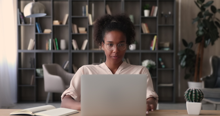 Beautiful young african ethnicity businesswoman in eyeglasses looking on computer screen, thinking of problem solution, looking for inspiration, involved in creative laptop work in modern home office. Royalty-Free Stock Footage #1070466127