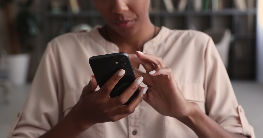Close up young african mixed race woman holding smartphone in hands, swiping pages in dating application, watching funny photo or video content in social network or choosing goods in internet store. Royalty-Free Stock Footage #1070466151