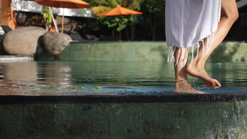 Low section of female legs walking along the edge of a pool | Shutterstock HD Video #1070467948