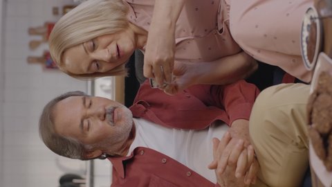 The old blond woman looks at her husband on coffee horoscope, they make comments together. Coffee fortune telling, having fun together, fortune telling concept.Video for the vertical story.