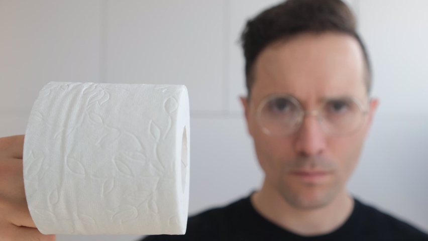 Soft selective focus. Toilet paper against the background of a blurry portrait of a Caucasian youth-holding toilet paper, basic necessities during quarantine and self-isolation