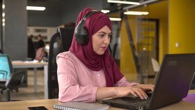 Islamic business woman in hijab with headphones and microphone are working in the office. Arab businesswoman working in customer service center using headset