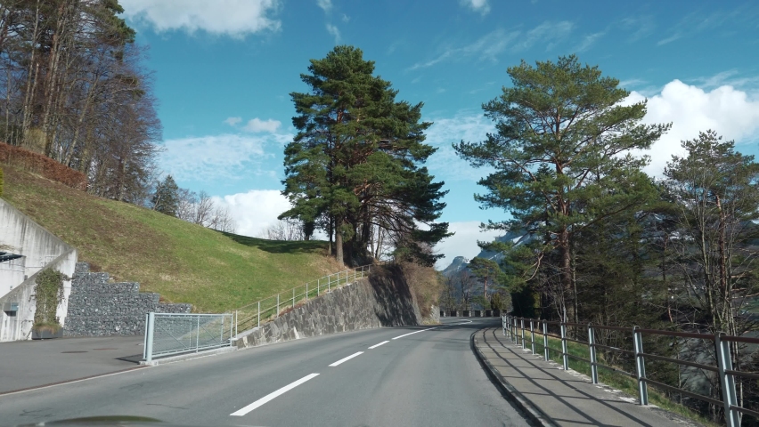 Traveling by Car along Mountain Road. POV Windshield Hood View On Picturesque Swiss Alps. Spring Switzerland Europe. Slow motion