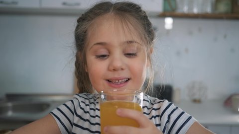 Little girl drinks juice. Organic fruit drink. Girl with glass of orange juice. Organic healthy juice. Little girl at home with drink. Child drinks juice. Organic healthy products concept.
