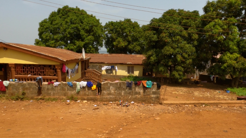 KISSI, SIERRA LEONE - 3 FEB 2021: Freetown Sierra Leone mountain village dirt roads POV fast. West Africa suffers with extreme poverty. Congested crowded street. Tropical climate environment. 