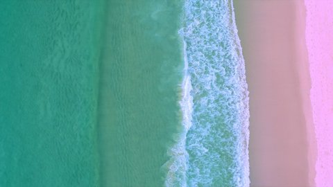 Amazing sea Aerial top view ocean blue waves break on pink sand beach waves crashing against an empty beach.Sea waves and beautiful pastel color romantic sand beach High quality video Bird's eye view