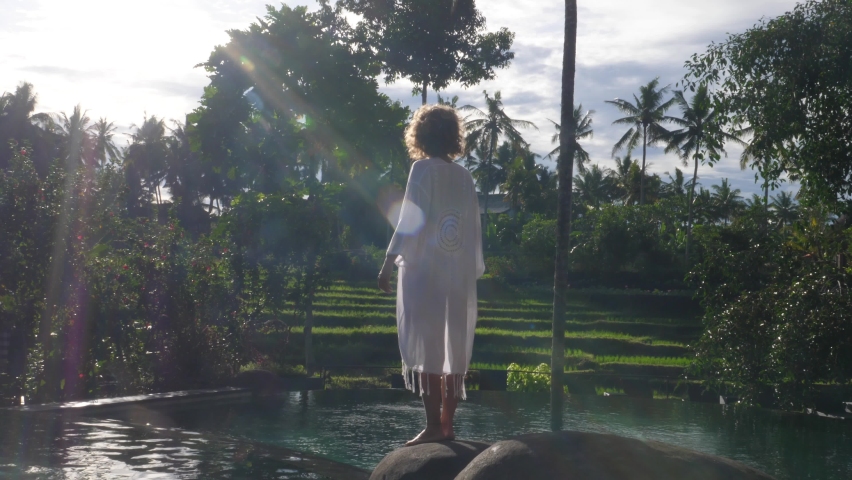 Back view of woman raising her hand to express joy, gratefulness and salute the sun. Mindfulness in Bali | Shutterstock HD Video #1070489416