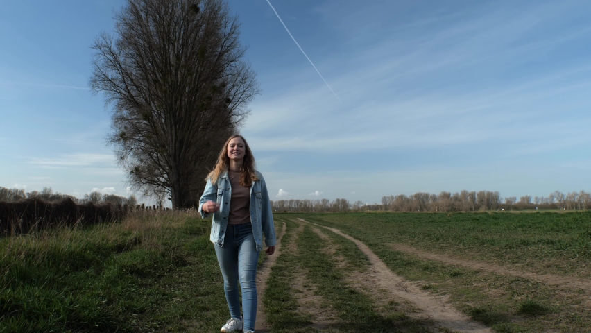 [4k] young woman in denim with flower walking towards camera turning in jump outdoors