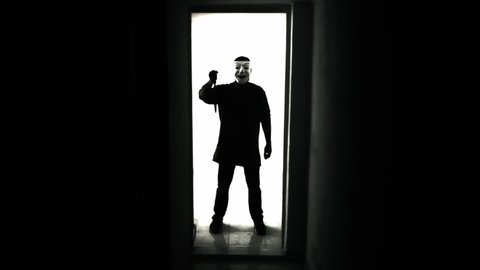Extreme silhouetted shot: a scary encounter in a basement with a killer wearing a white mask, running at us with a knife. 
