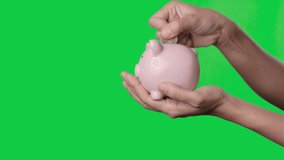 Saving money concept, Asian woman hand putting money coin into piggy bank on chroma key green screen background. Alpha Channel. - Powered by Shutterstock - Get 15% off with code: PIKWIZARD15
