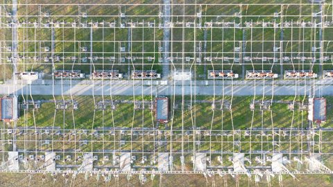 Electrical substation: transformers and grid of pylons, lines and wires. Long-range energy transmission and high voltage electric power distribution system. Aerial drone top down view.