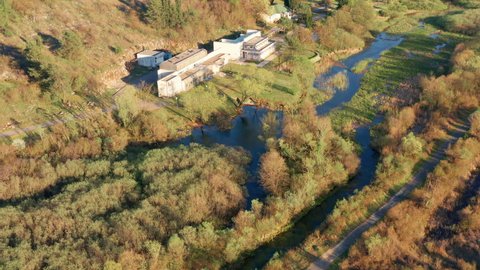 Groundwater purification plant (factory) for a small town water supply system - drainage basin and watershed, excess flowing in a blue stream through green and orange landscape in autumn.