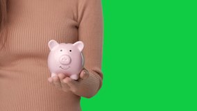 Saving money concept, Asian woman hand putting money coin into piggy bank on chroma key green screen background. - Powered by Shutterstock - Get 15% off with code: PIKWIZARD15