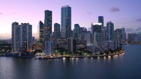 Downtown Miami at pink sunset. Scenic Miami skyline panorama. Aerial view of downtown at night scene. Beautiful urban landscape of coastal bay city at dusk. City lights in purple sunset light. Florida