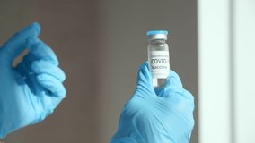 A close-up view of female arms opening a test tube with a vaccine. A nurse in blue medical gloves holding a treatment ingredients. High quality 4k footage