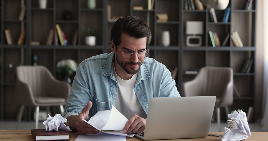 Anxious stressed young male manager employee entrepreneur in eyeglasses crumping paper documents, feeling nervous analyzing data statistics reports, standing and leaving workplace, deadline concept. | Shutterstock HD Video #1070517007