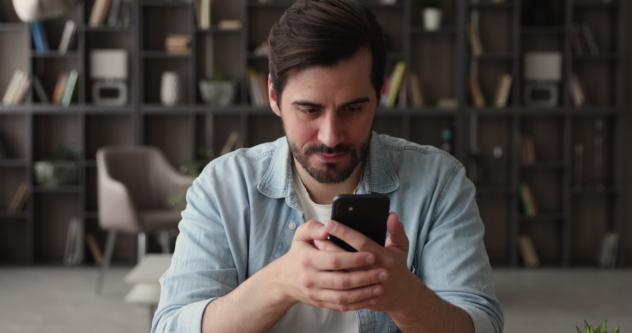 Sincere emotional young handsome man looking at cellphone screen, feeling excited of getting message with amazing news, celebrating betting auction online lottery giveaway win, internet success. Royalty-Free Stock Footage #1070517046