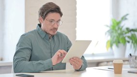Middle Aged Man making Video Call on Tablet in Office 