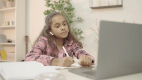 Biracial girl making video call on laptop, talking to teacher online, studying