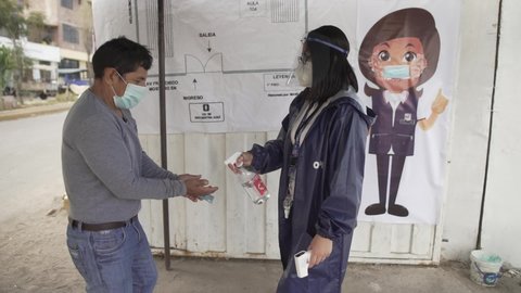 Arequipa, Peru. Sunday, April 11, 2021: Voters wearing masks to slow the spread of the new coronavirus have their temperatures measured and sprayed with alcohol at the entrance of a polling station.