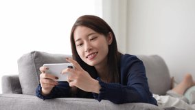 attractive asian woman playing game on smart phone