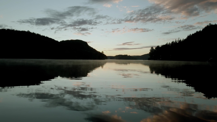 Dark calm lake hidden in the forest with a sky reflections on the water