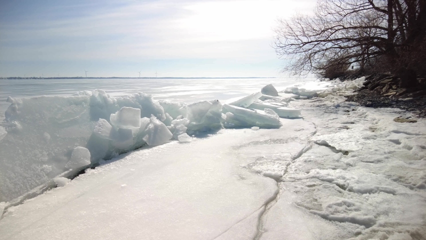 Early Spring along the northern shore of Lake Ontario, Canada. Beautiful, sunny day. Ice floes are pushed up by the wind and wave action. Slow L to R pan.
