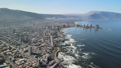 Iquique Chile. Drone aerial view, modern coastal city waterfront, buildings and Pacific ocean waves on sunny day