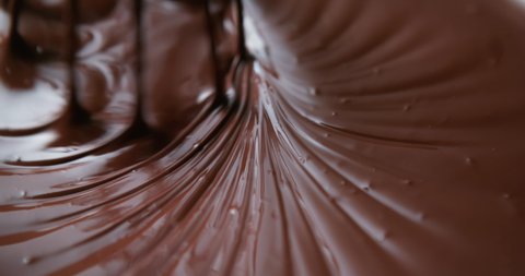 Close-up chocolatier mixing melted liquid chocolate with steel whisk. Hot chocolate mix and swirl in bowl. Cooking handmade chocolate dessert and candies. Confectionery concept