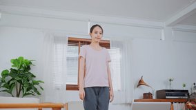 Asian Beautiful young woman stay at home, working out follow instructions video from online trainer. Active girl doing lockdown activities in house Yoga, Pilates exercise during Coronavirus pandemic.