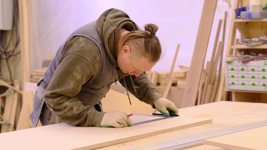 Close up. Carpenter holding a measure tape on the work bench. Woodwork and furniture making concept. Carpenter in the workshop marks out and assembles parts of the furniture cabinet