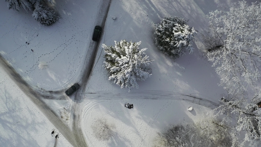 Two Cars Driving on Curvy Country Roads in White Winter Landscape, Top Down Aerial