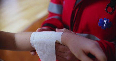 Doctor wrapping bandage on injured hand, closeup view