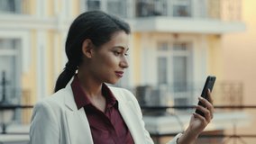 Attractive mixed race businesswoman saying hi outdoors. Smiling female entrepreneur video chatting at urban street. Happy business woman having conversation outside