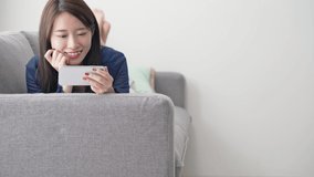 Young asian woman watching video with a smart phone. Slow motion.