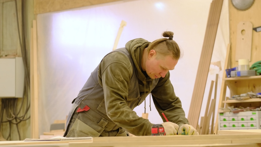 Close up. Carpenter holding a measure tape on the work bench. Woodwork and furniture making concept. Carpenter in the workshop marks out and assembles parts of the furniture cabinet