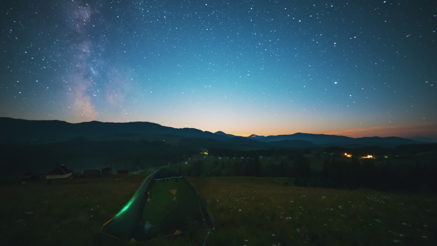 Camp tent under the starry sky and moving Milky Way Galaxy over the high mountains, night landscape timelapse