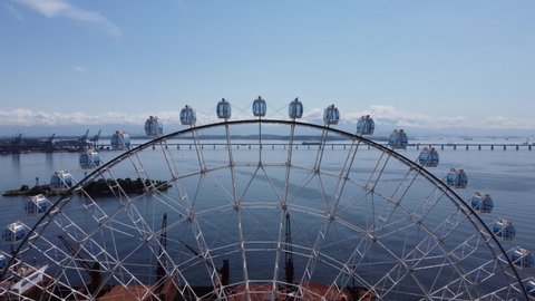 Ferris wheel in coastal city, Rio de Janeiro. Tropical vacation. Travel destination. Panorama landscape of Major Ferris Wheel of Latin America at downtown of Rio de Janeiro, Brazil. Rio Niteroi Bridge