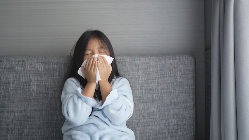 Asian child or kid girl sick and sneezing on nose with cold cough on tissue paper from influenza coronavirus and allergy weak or virus bacteria from PM 2.5 dust weather or smoke at hospital or home 4K Royalty-Free Stock Footage #1070575009