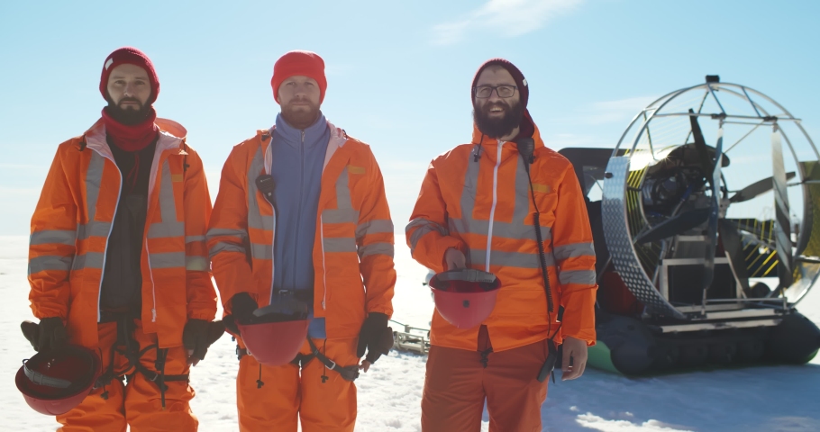 Professional lifesavers putting on hardhat working in arctic. Portrait of coast guard team in safety gear posing at camera outdoors over frozen lake