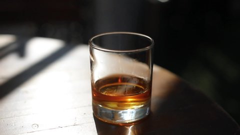 HD high angle tracking shot footage of a whisky glass, with shallow depth of field.